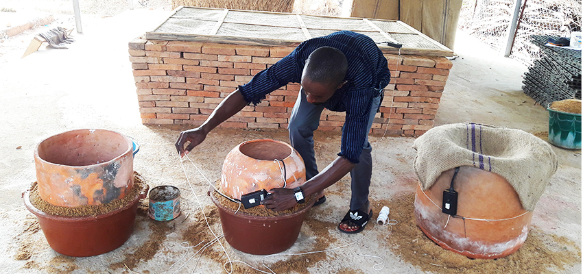 Attaching a sensor to a pot-in-pot evaporative cooler in Bamako, Mali. Photo: Ousmane Sanogo