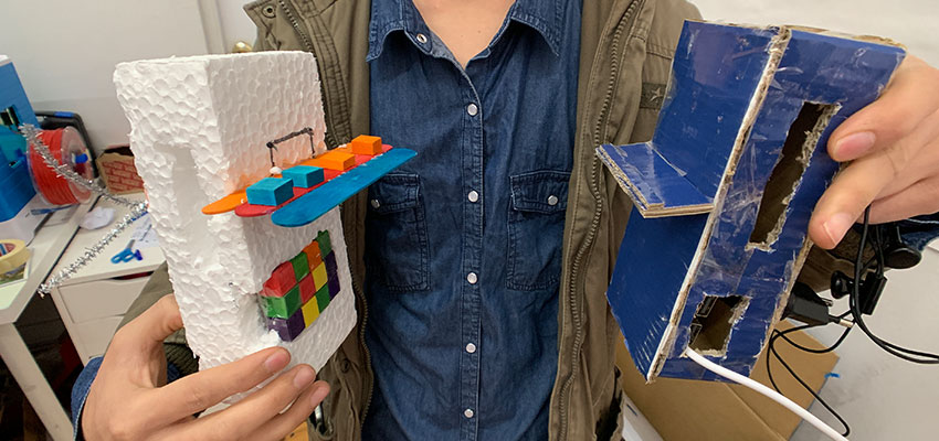 A student holding the sketch models he created to demonstrate his ideas for a power bank case.