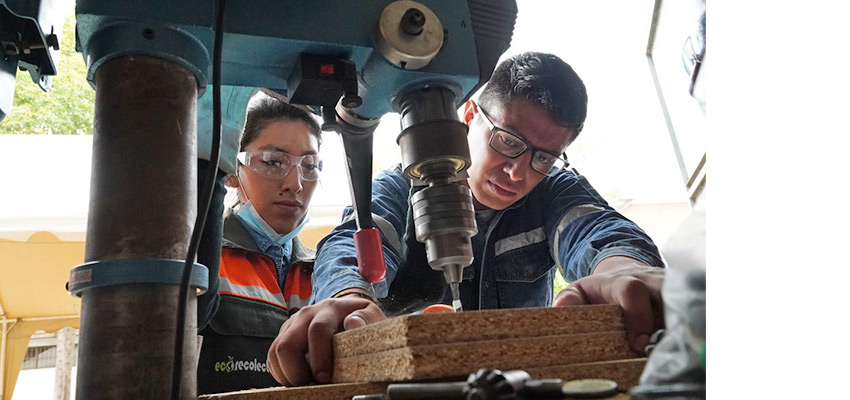 Two people working on a drill press.