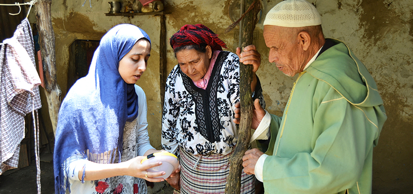 Two women and a man looking at a small solar light held by one of the women.