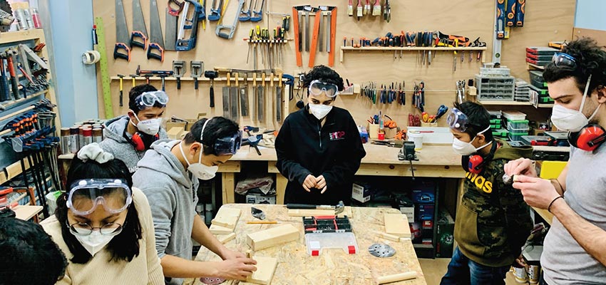 MIT D-Lab students teaching the refugee youth on how to use woodworking tools to design a phone stand.