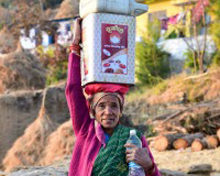 A woman carrying drinking water collected at a natural spring on her head.