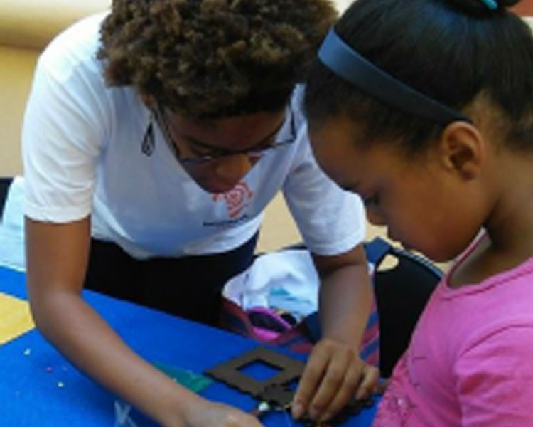 Netia assisting a young participant in assembling her Solar USB Charger at a Mbadika Workshop in Cape Town, South Africa.