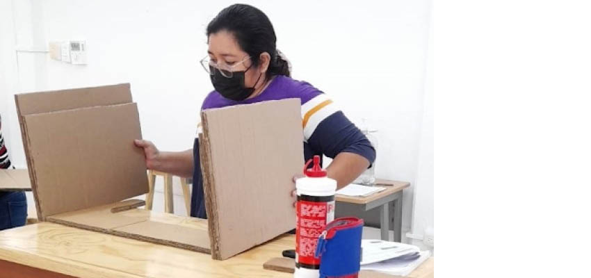 Women sitting at a table with cardboard prototype.
