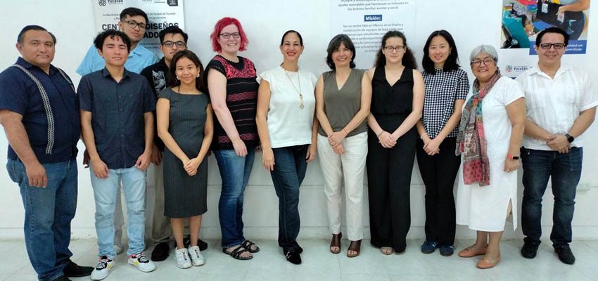A group of 12 students and adults pose in front of the a white wall. Among them are MIT D-LAB, Uady students, and staff from Perkins and SEGEY.