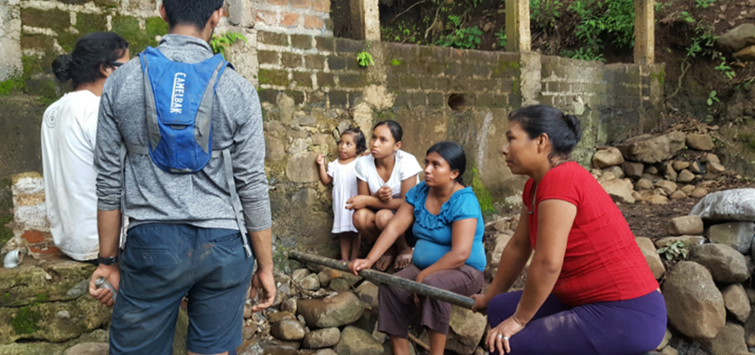 Samir Wadhwania '18 (second from left) and Geovany Moreno talking with the women of El Sauce, El Salvador about to describe how to connect the pipes that would provide them with water for laundry.