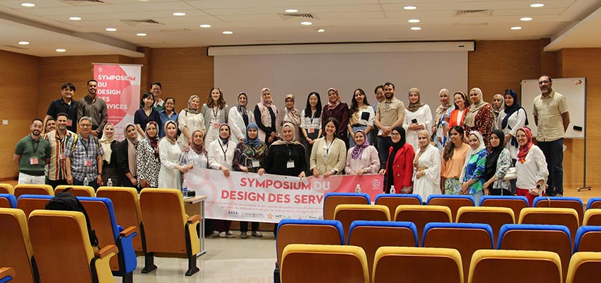 The MIT D-Lab team at the Maternal Healthcare Symposium in Morocco with healthcare professionals, translators, and project partners. The sign says, "Symposium Du Design Des Service," translating to "Service Design Symposium." Photo: Courtesy Global Care Young Min Ju (Thomas).