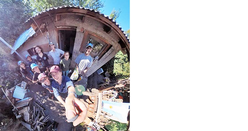 .5 selfie of 8-10 people in front of a corrugated tin roof building.