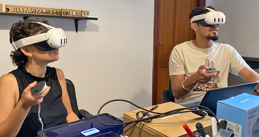 A woman and a man seated at a table wearing VR sets.