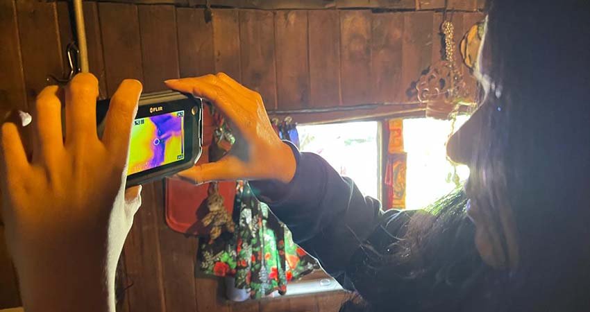 Close up of a woman at right, in profile, holding up a cell phone.