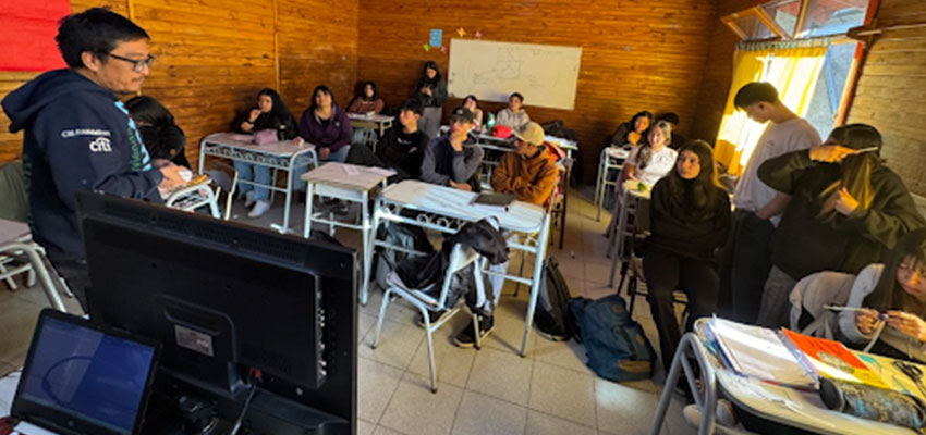 A small group of young adults seated and standing in a classroom.