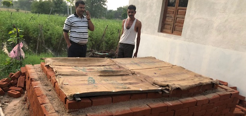 Vivek Vishal from CInI and Rameshbhai Kuberbhai Parmar inspecting a brick evaporative cooling chamber (ECC) constructed in Mandavav village, Dahod district Gujarat with bamboo and jute sacks used as the top cover