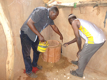 Two men watering a pot-in-pot cooler.