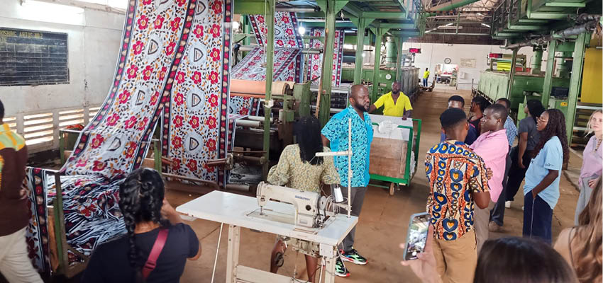 Several people standing in a textile printing factory.