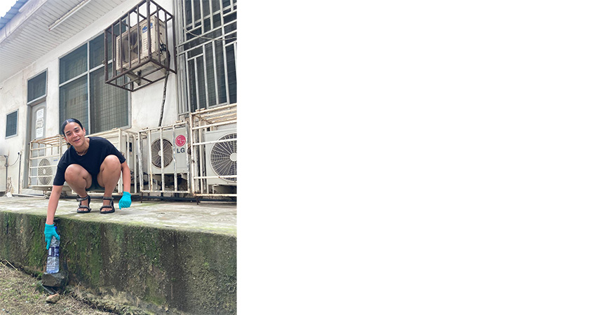 Woman crouched undernearth the outside of an airconditioning unit.