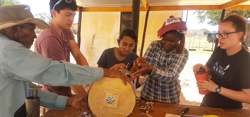 D-Lab Students Sloan and Bhattacharjee along with some of the community members working on the bean thresher.