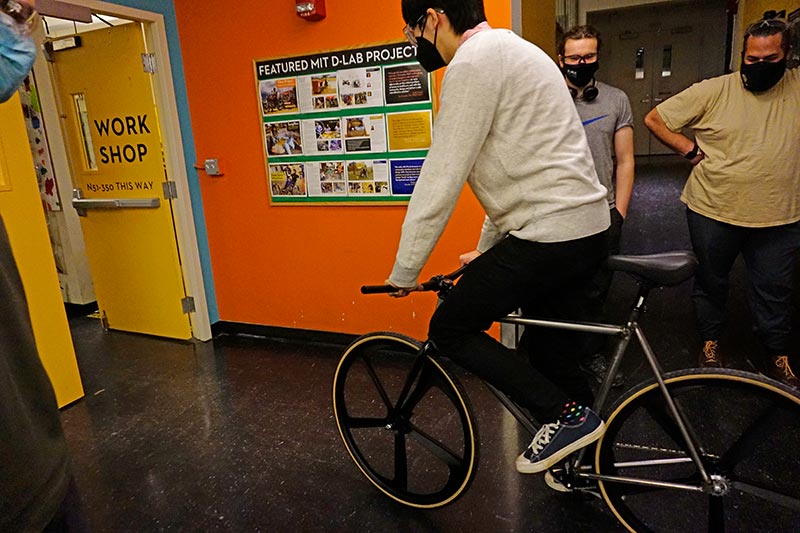 man riding bike through hallway with people looking on