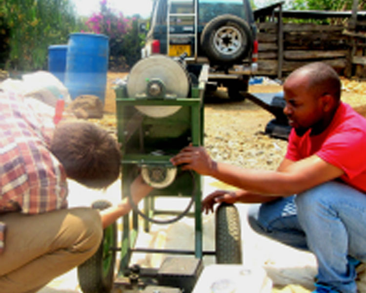 Elliot (left) works on the Multicrop Thresher with a colleague.