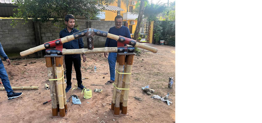 Two men standing behind a bamboo structure.