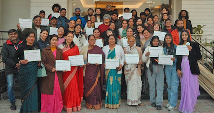 30+ people holding certificates, standing for group portrait - mostly Indian women.