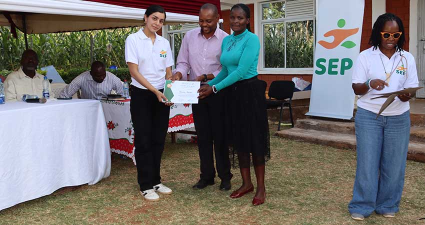 Three people stand outside holding a certificate.