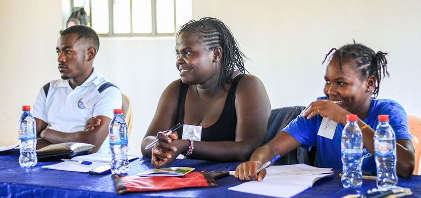 A man and two women seated next to each other on one side of a table.