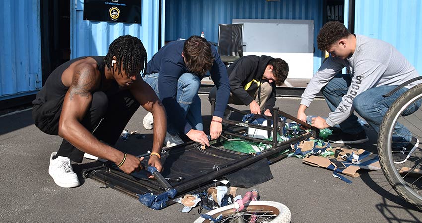 Four young men bent over a technical project on the ground.