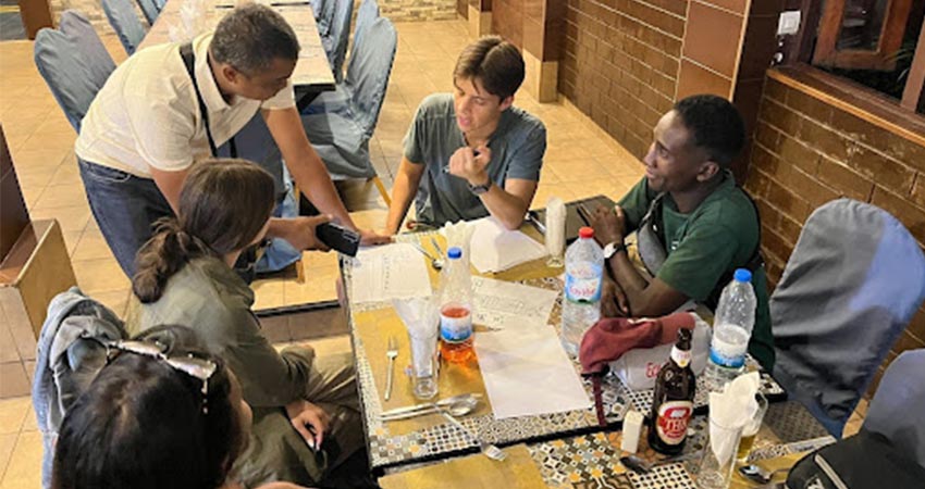 Five people working around a table covered in documents and plastic water bottles.