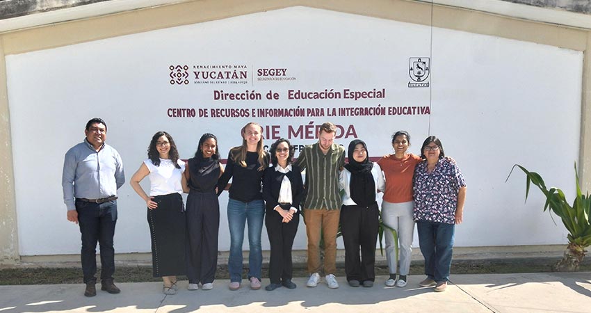 A group of nine men and women standing in front of a building.