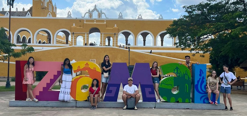 Six people standing in front of a colorful mural.