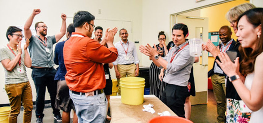 Participants from the 2019 Inclusive Innnovation Professinal Education course standing and rejoicing after the success of a participatory design challenge entailing minimal resources. 