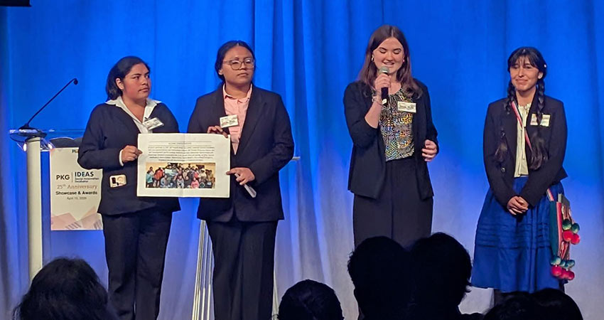 4 women standing ona stage, one holding a microphone