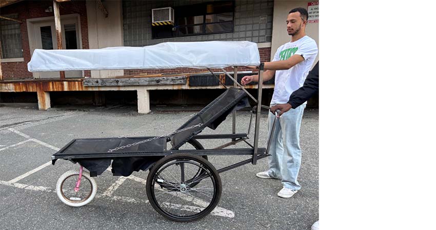 Man standing by a rolling shaded stretcher.
