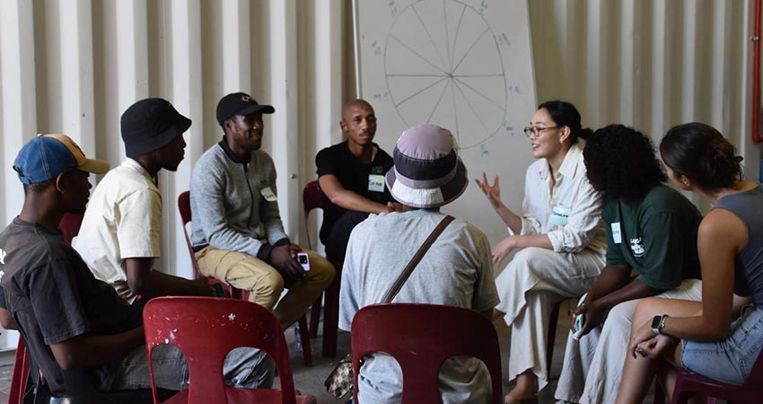 Group of eight people seated in chairs in a circle.