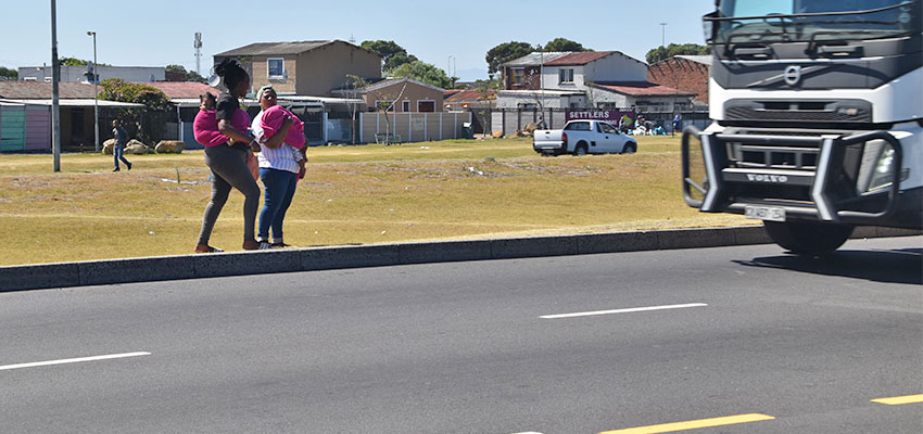 Two women about to cross a busy highway.