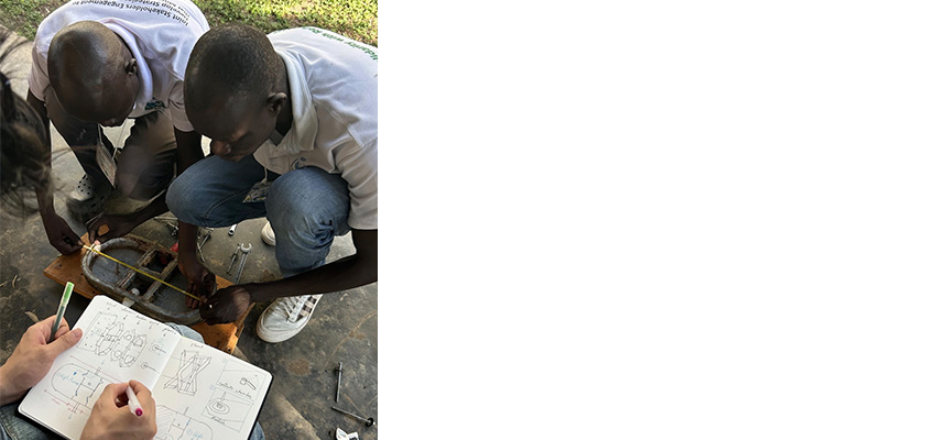 Two men crouched next to each other in the ground, hand making notes in a notebook in the foreground.